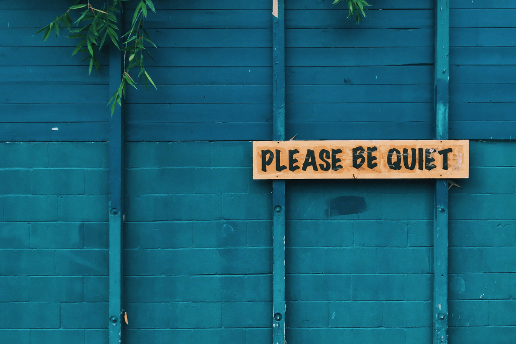 Feature image - a blue painted fence with a sign saying please be quiet