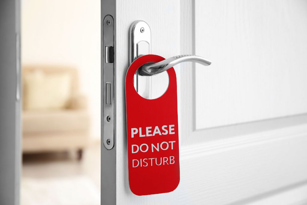 Hotel door with a do not disturb sign hanging on the door handle.